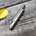 Compact multitool on wooden surface near yellow leaf